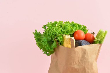 Pembe arka planda taze sebzeli kağıt torba. Market alışverişi kavramı