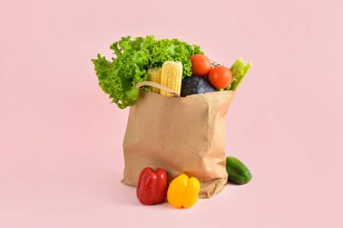 Pembe arka planda taze sebzeli kağıt torba. Market alışverişi kavramı