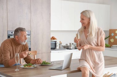 Olgun bir çift mutfakta yemek yiyor.