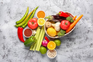 Farklı taze sebzeler ve mavi arka planda mısır gevrekleri olan hasır bir kase.