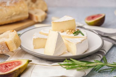 Gri arka planda lezzetli Camembert peyniri parçaları ile tabak.