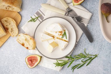 Gri arka planda lezzetli Camembert peyniri parçaları ile tabak.