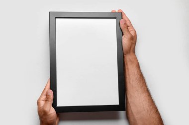 Beyaz arkaplanda boş fotoğraf çerçevesi tutan adam