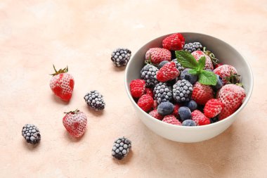 Bej rengi grunge arka planda nane yapraklı bir kase donmuş dut.