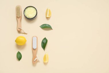 Bowl of lemon body scrub with massage brushes on beige background