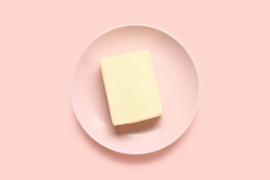 Plate with fresh butter on pink background