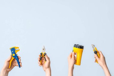 Electrician hands with tools on grey background