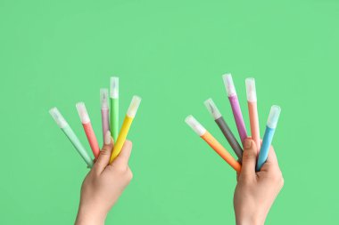 Female hands with felt tip pens on green background