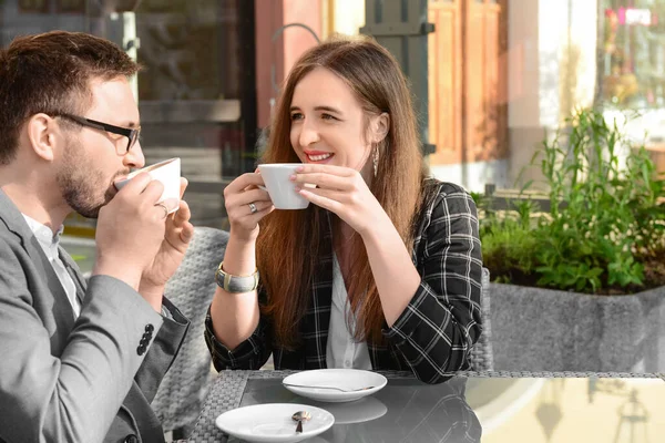 Güzel, mutlu bir çift restoranda oturuyor ve güneşli bahar gününde kahve içiyor.