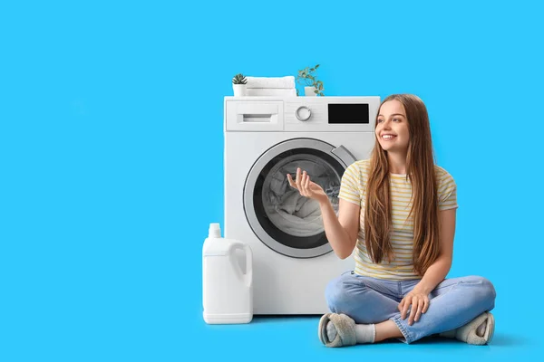 Söt Ung Kvinna Sitter Nära Tvättmaskin Blå Bakgrund — Stockfoto