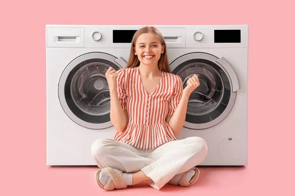 Jovem Feliz Sentada Perto Máquinas Lavar Roupa Fundo Rosa — Fotografia de Stock