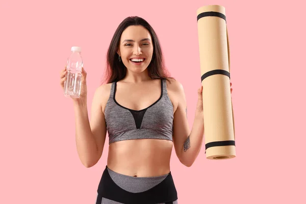 有瓶装水和粉色背景的健身垫的胖女人 — 图库照片