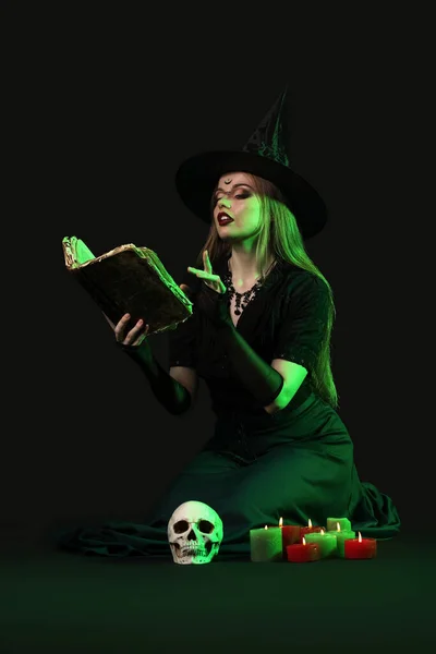 美丽的年轻女巫带着黑暗背景的魔法书 — 图库照片