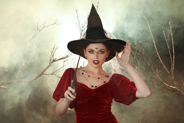 暗い背景に魔法の杖で美しい若い魔女 — ストック写真