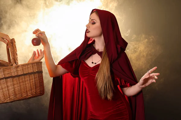 色の背景にリンゴとバスケットが付いている美しい若い魔女 — ストック写真