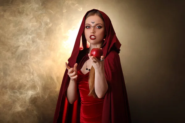 色の背景にリンゴが付いている美しい若い魔女 — ストック写真