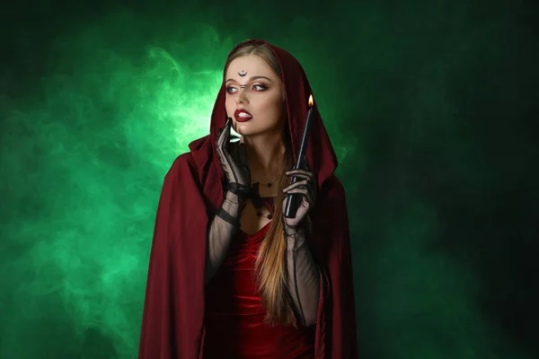 美丽的年轻女巫 背景是深绿色的蜡烛 — 图库照片