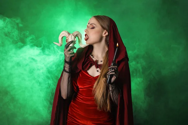 緑の背景にキャンドルと羊の頭蓋骨を持つ美しい若い魔女 — ストック写真