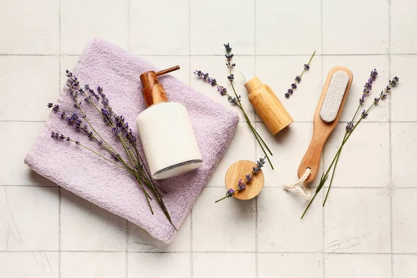 Composition with cosmetic products, bath supplies and lavender flowers on light tile background