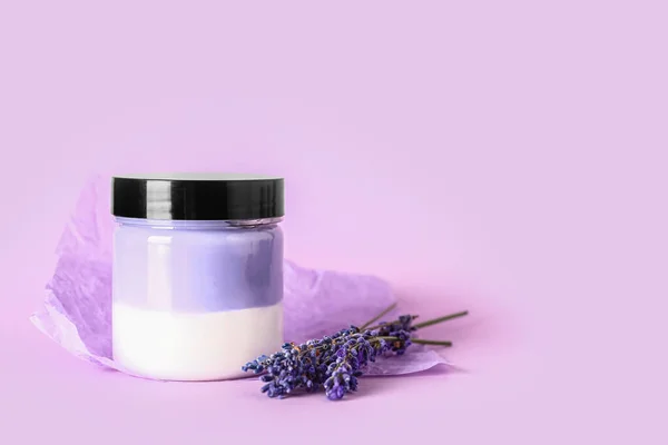 Jar of cosmetic product and lavender flowers on lilac background