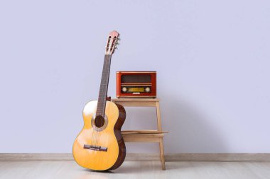 Işık duvarının yanındaki Retro radyo alıcısı ve gitar