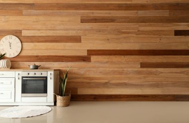 Ahşap duvarın yanında pişirme kabı ve bitkisi olan modern elektrikli fırın.