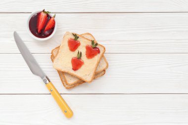 Beyaz ahşap arka planda çilek reçelli lezzetli tostlar.