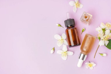 Esaslı yağ şişeleri ve leylak arkaplanda güzel yasemin çiçekleri olan kompozisyon