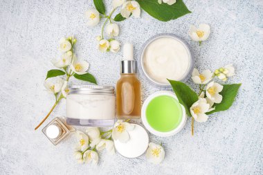 Farklı kozmetik ürünleri ve açık arkaplanda güzel yasemin çiçekleri olan kompozisyon