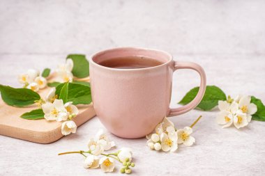 Bir fincan lezzetli çay ve arka planda güzel yasemin çiçekleri.