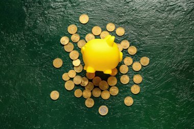 Yeşil arka planda bir sürü bozuk parası olan domuz kumbarası