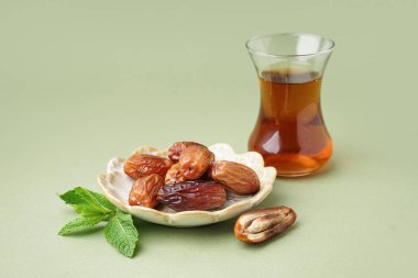 Kurumuş hurma tabağı ve yeşil zemin üzerinde bir bardak Türk çayı.