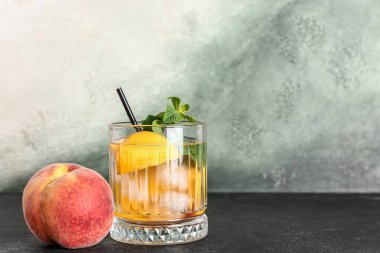 Bir bardak taze şeftalili limonata ve siyah masada nane şekeri.