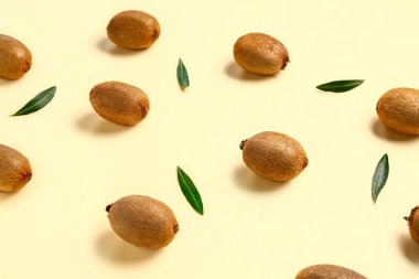 Bir sürü taze kivi ve sarı arka planda yapraklar