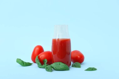 Mavi arka planda bir şişe lezzetli domates suyu.