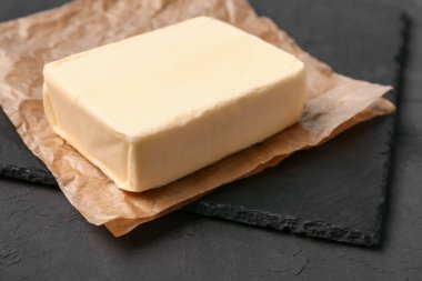 Baking paper with fresh butter on black background