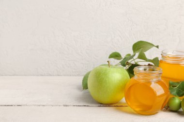 Beyaz ahşap masada Rosh Hashanah kutlaması (Yahudi Yeni Yılı) için elmalı bal kavanozları