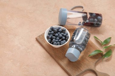 Yaban mersinli spor şişeleri ve pembe masada bir kase böğürtlen.