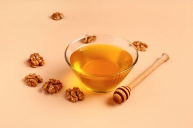 Bej arka planda ceviz ve dipli bir kase tatlı bal.