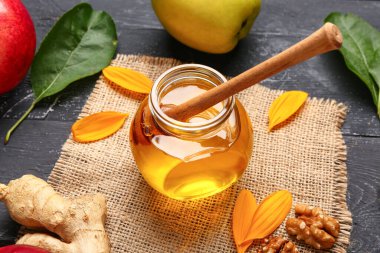 Siyah ahşap arka planda ceviz, elma ve zencefilli bal kavanozu