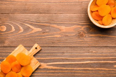 Ahşap arka planda lezzetli kurutulmuş kayısıları olan yemek ve kase.