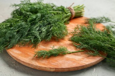 Gri arka planda taze dereotu olan ahşap tahta.