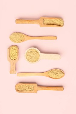 Ahşap kepçe ve kaşık pembe arka planda zencefil tozu