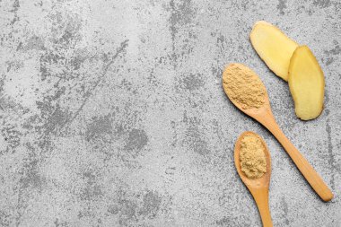 Taze zencefil kökü dilimleri ve mavi arka planda kurutulmuş toz ile ahşap kaşıklar.