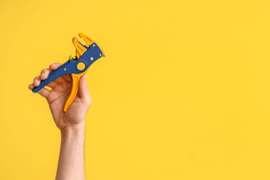 Sarı arka planda tel sökücü ile elektrikçi eli