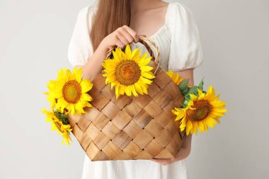 Hasır sepette güzel ayçiçekleri olan genç bir kadın.