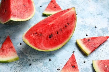 Açık mavi zemin üzerinde olgun karpuz parçaları olan kompozisyon, yakın plan.