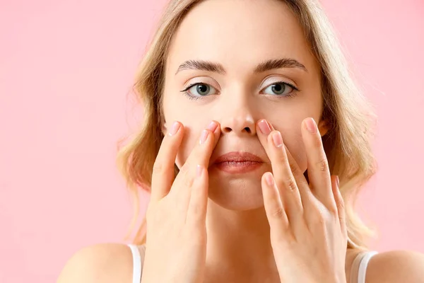 Young woman doing face building exercise on pink background, closeup