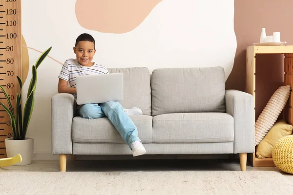 stock image Little African-American boy with laptop studying computer sciences online at home