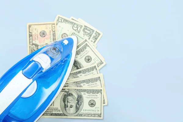 stock image Electric iron with dollar banknotes on blue background